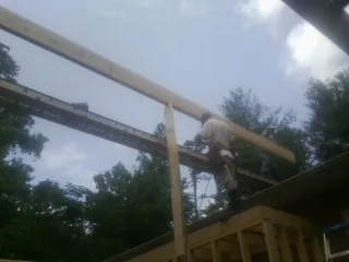 Carpenter setting a ridge beam over a new addition frame — Ice Dam Removal by Roofing Brothers in Morehead City