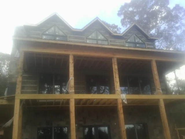 Dormers and porch framing on a large log home under construction — Roof Coating work by our crew in Morehead City