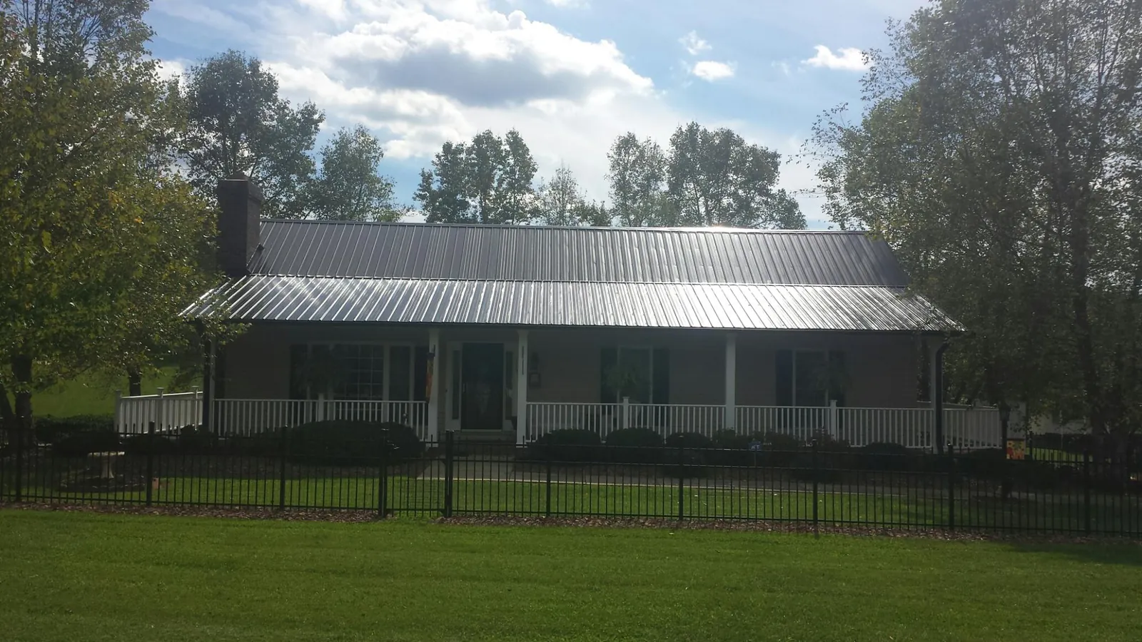 Gray metal roof on a brick ranch with a full width front porch — Gutter Guard Installation work by our crew in Morehead City